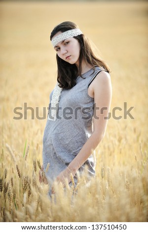 Young woman in a grey linen dress posing in the field