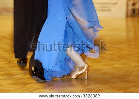 Dancing feet of a woman dressed in blue dress wearing golden shoes and of a man dressed in a tux moving away