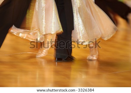 Dancing woman\'s feet in glossy pink sandals on orange floor with one man\'s foot in between