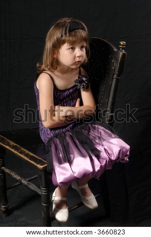 Dressed up little gild sitting on old chair looking up surprised
