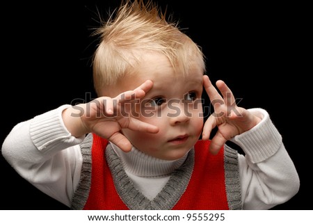 Close-up of a boy in red vest looking sideways making faces playing with his hands horizontal