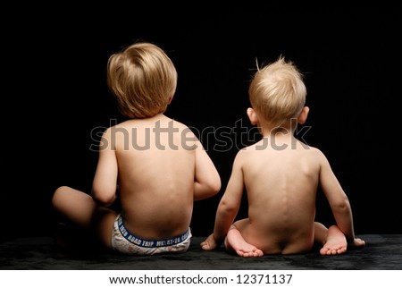 Two boys against black background turned their backs to the camera