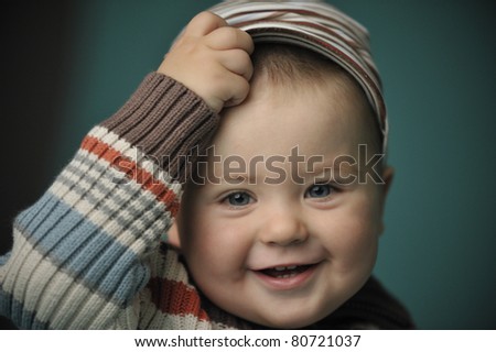 Closeup soft portrait of a small boy scratching his forehead laughing