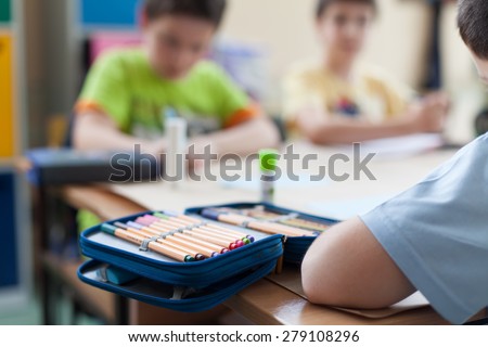 open pencil box on wooden classroom table