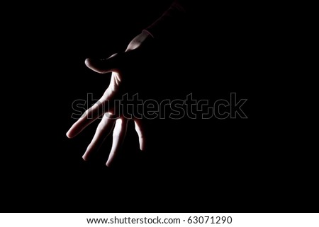 backlit outline of spooky human hand isolated on black for text