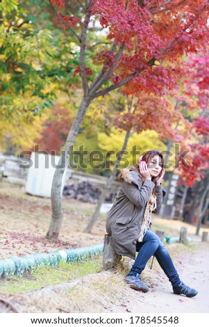 woman listening music outdoors in autumn season.