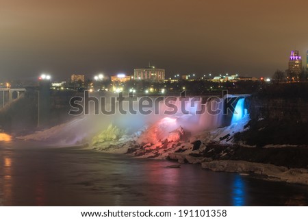 Niagara Falls lit at night by colorful lights between the Canadian province of Ontario and the U.S. state of New York.