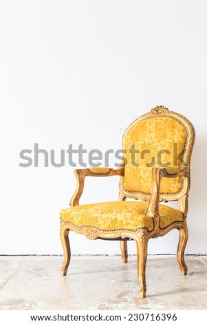Yellow vintage armchair on white wall.