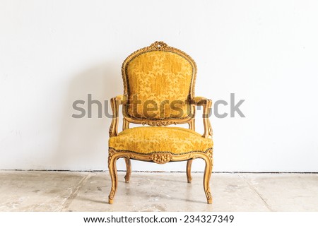 Yellow vintage armchair on white wall.