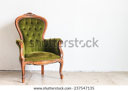 Green vintage armchair on white wall.