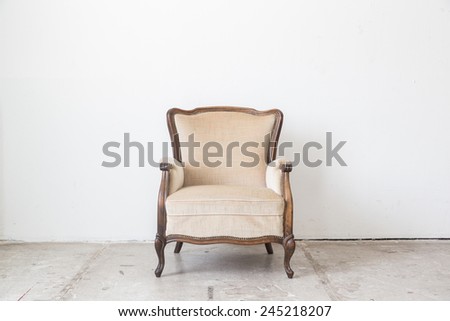 Beige vintage armchair on white wall.