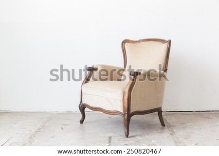 Beige vintage armchair on white wall.