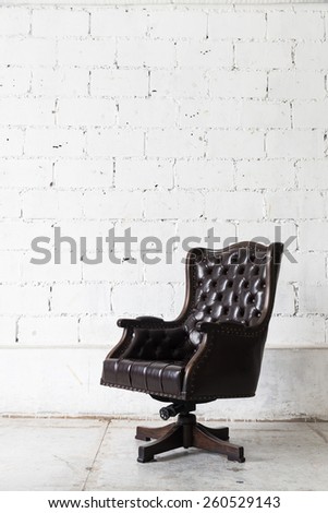 Black vintage armchair on white wall.