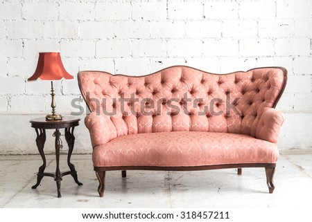 Pink vintage sofa and lamp on white wall.