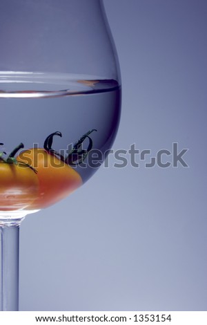Close up of tomato inside the wine glass. soft lightning is grey+blue background