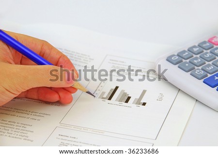 Writing on the test paper with calculator at background