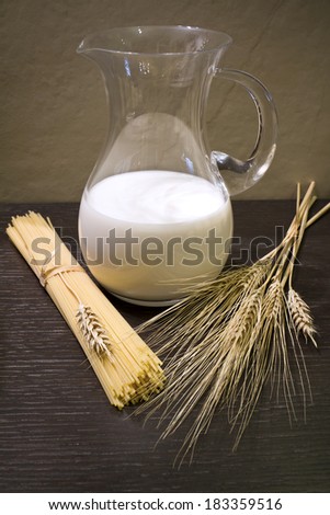 Milk in the pitcher, spaghetti, corn ears on wooden background