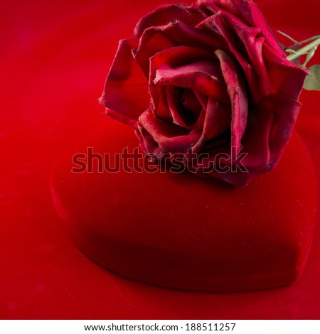 Heart\'s shape red velvet box with rose on red background