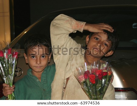 KARACHI, PAKISTAN - OCT. 11: Unidentified poverty-stricken, street kids sell roses at a commercial street in Karachi, Pakistan on October 11, 2007