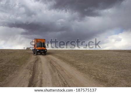 PAWNEE NATIONAL GRASSLANDS, COLORADO, USA - April 8: Custom orange RV truck driving on dirt road on April 8, 2014 at Pawnee National Grassland, Colorado, USA.