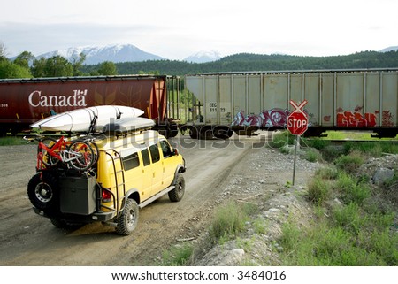 Yellow 4x4 van at railroad crossing, Canada