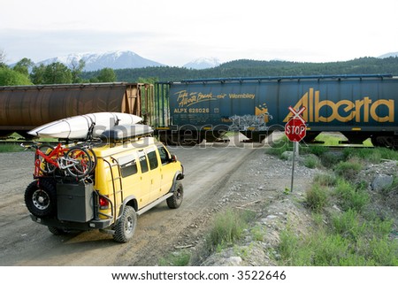 Yellow 4x4 van at railroad crossing, Canada
