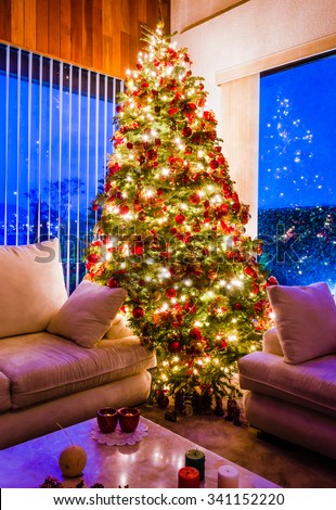 Christmas tree with golden lights in a cozy living room with windows at the evening