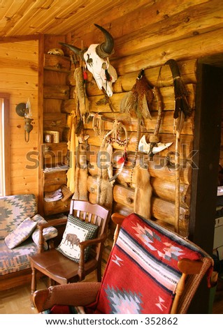 Native American & south western art and artifacts hang on log cabin wall.