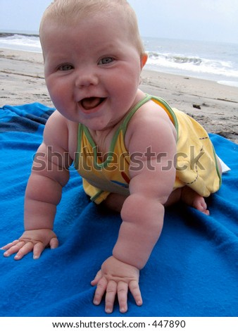 Happy beach baby crawls across a bright blue blanket.