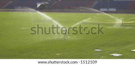 Water sprinkler showering football ground grass in the stadium