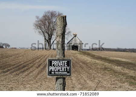 A private property sign posted in front of an abandoned rural property