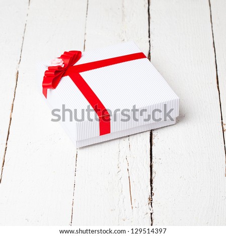 Gift box with red ribbon on old wood. Vintage holiday background.