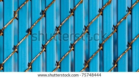 Close-up Fence Detail of Chain Link Showing Rust with Solid Blue Infill Slats