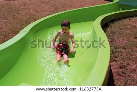Enjoying the Slide/Young boy enjoys sliding  	down the water slide