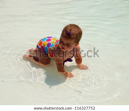 Kneeling in the water/Baby girl kneels in the shallow 	water to cool off