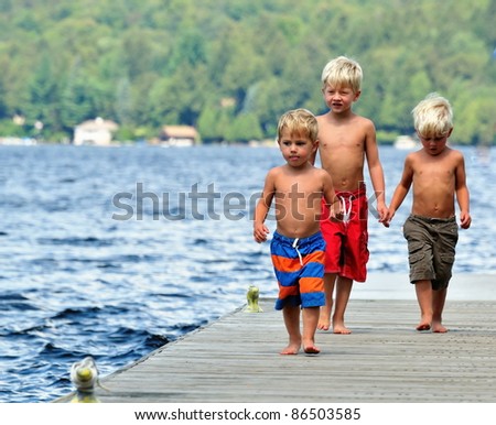 Three brothers walk along the dock on a sunny day