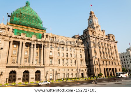 SHANGHAI, CHINA - AUGUST 1: A few stray cars pass by the HSBC Building and the Customs House on August 1, 2013 in Shanghai, China. The Bund is one of the most popular tourist attractions in Shanghai.