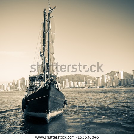 A vintage shot of a traditional junk ship sailing along Victoria Harbor in Hong Kong.