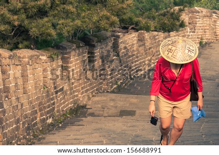 A young woman climbs the arduous steps of the Great Wall of China.