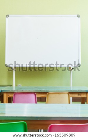 Empty classroom with whiteboard, desks and chairs.