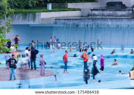 KUALA LUMPUR, MALAYSIA - DECEMBER 28: People of all ages play in the public wading pools at KLCC Park on December 28, 2013 in Kuala Lumpur, Malaysia.