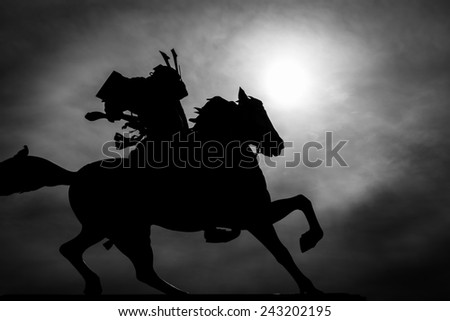 Black and white silhouette of a samurai on horseback.