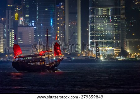 A junk ship sails through Victoria Harbor at night in Hong Kong.