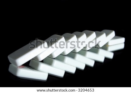 A row of toppled dominoes on a black reflective surface