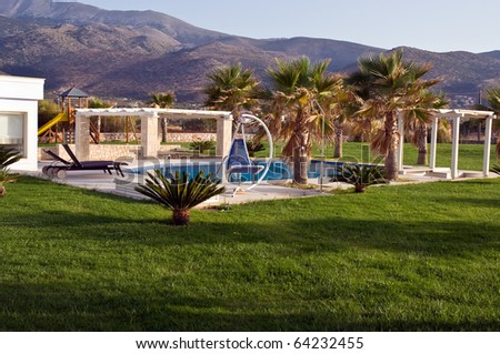 Swimming pool, sunbeds and palms at luxury villa, Crete, Greece
