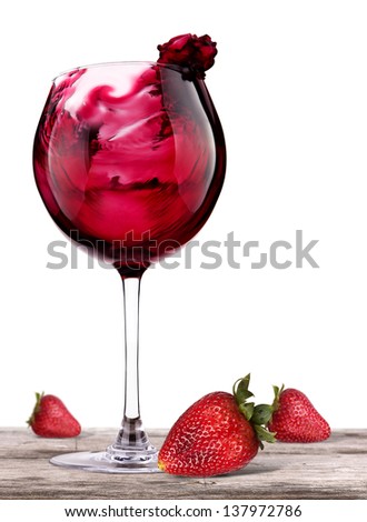 red wine splashing on a vintage wooden table with fresh red strawberry