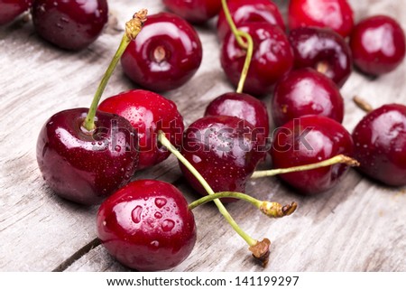 Cherries on wooden table with water drops macro background