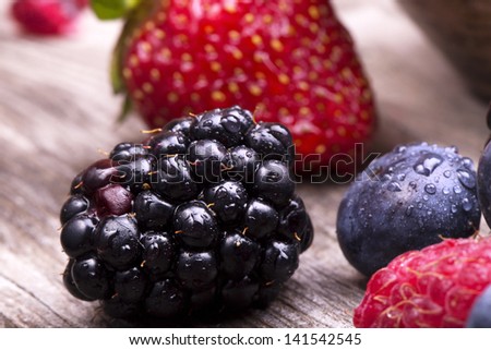 tasty summer fruits on a wooden table. Cherry, Blue berries,  strawberry, raspberries, Blackberries, pomegranate