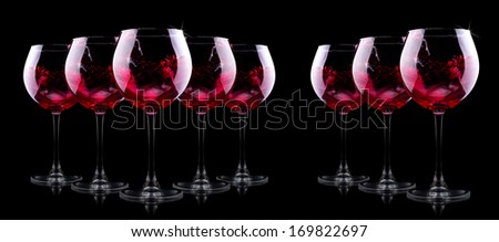 glass of red splashing wine on black background
