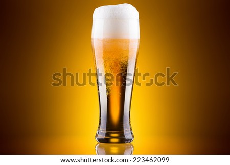 Frosty glass of light beer on a colored background